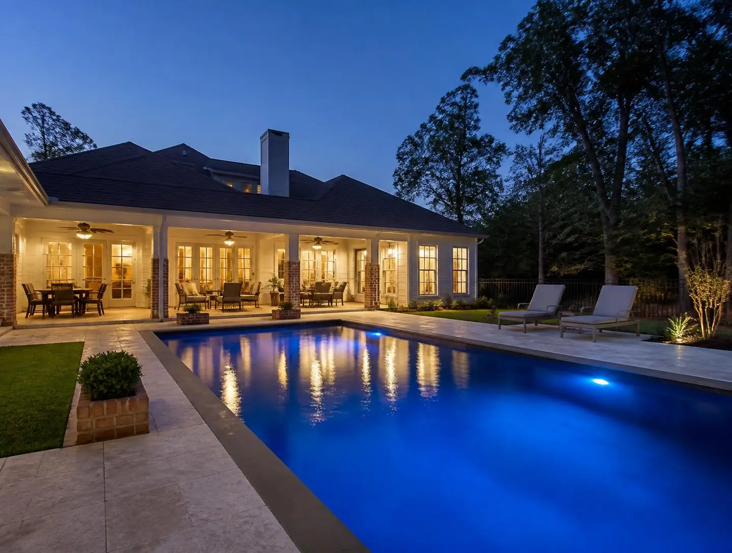 Swimming pool at night lit with blue LED lighting beside a modern patio