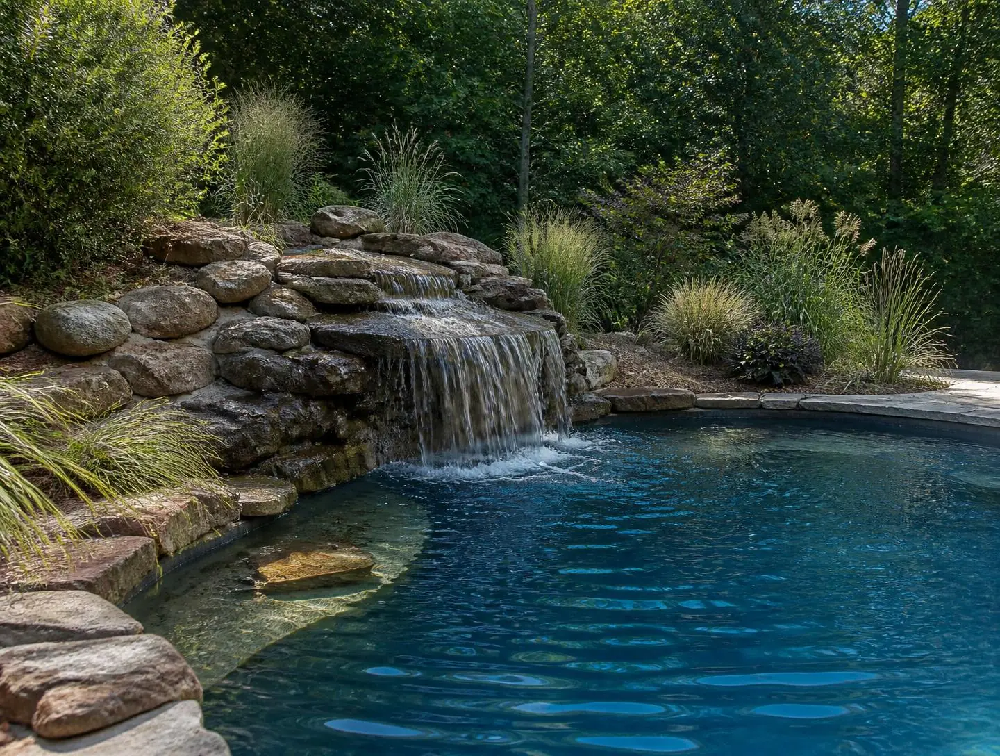 Freeform pool with natural rock waterfall and landscaped surround